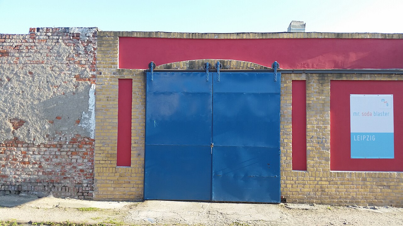 Portón metálico azul en un muro de obra